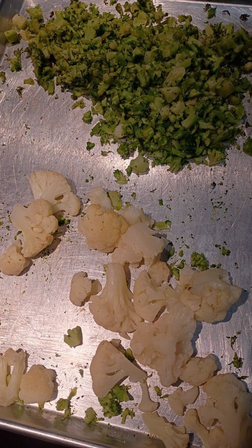 A sheet tray of chopped broccoli and cauliflower florets, prepped and ready
