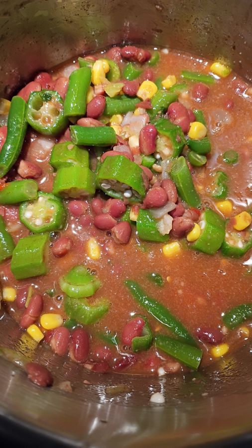 A pot of okra, red kidney beans, corn and green beans simmering in a spiced tomato broth